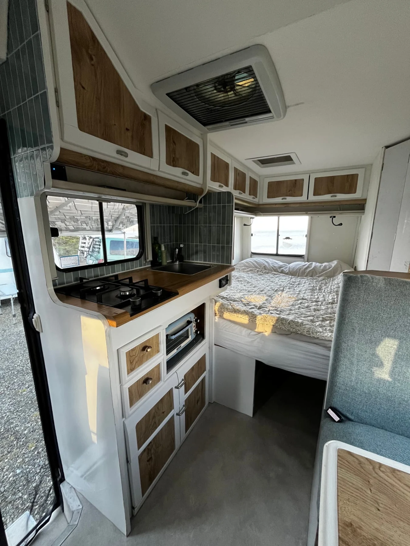 Camperinterieur met houten keuken, zitbank en slaapruimte